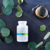 Cooper Complete Advanced Omega3 dietary supplement Bottle on a dark slate surface with green branches and several small stacked rocks