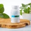 Cooper Complete Basic One Iron Free multivitamin and mineral bottle on a wood plank with cut and potted sage