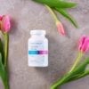 Cooper Complete Calcium Citrate Dietary Supplement bottle on a slate surface with several pink tulips
