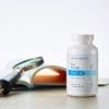 Cooper Complete Eye Health dietary supplement bottle on a tablet along side an open book with magnifying glass