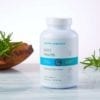 Cooper Complete Joint Health dietary supplement bottle on a marble surface with the herb rosemary in a wooden bowl