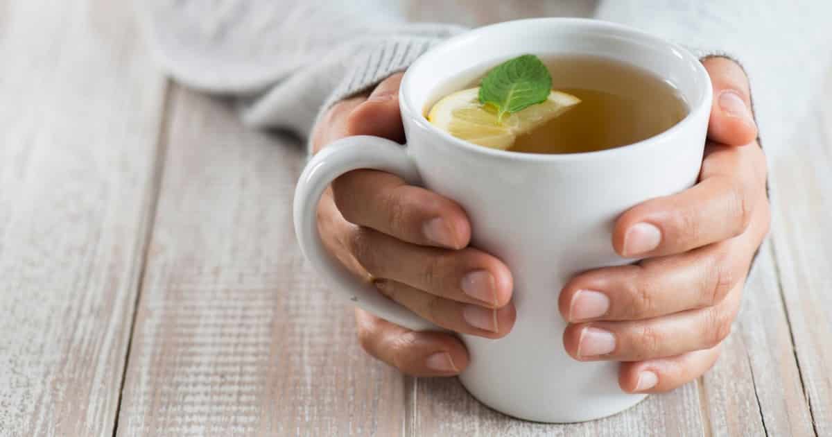 Cup of green tea being held