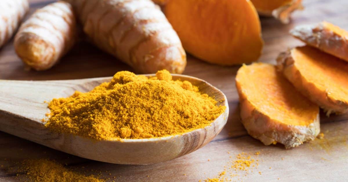 Turmeric powder and root on a wooden table, learn about turmeric supplement benefits