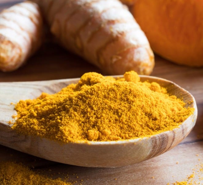Turmeric powder and root on a wooden table, learn about turmeric supplement benefits