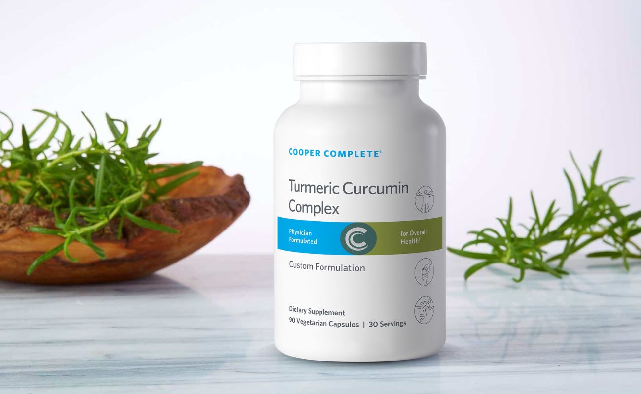 Photo of Cooper Complete Turmeric Curcumin Supplement bottle on a marble countertop surrounded by greenery.
