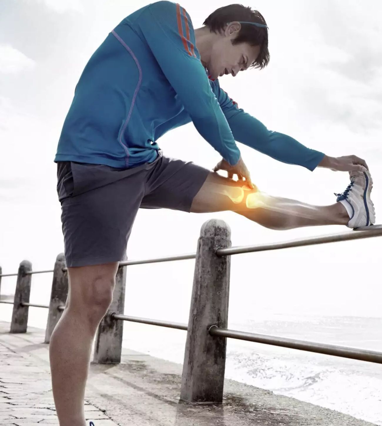 Photo of a young man stretching his legs by the ocean as part of his workout.