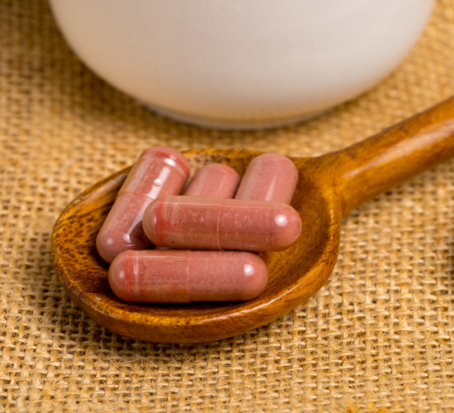 Photo of red yeast rice supplement pills on a wooden spoon