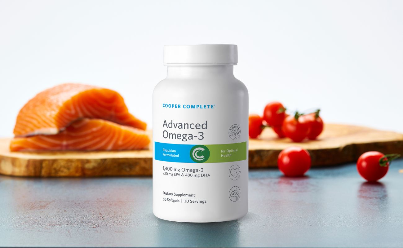 Photo of Cooper Complete Advanced Omega 3 Supplement bottle on a countertop with fresh salmon and cherry tomatoes on a cutting board