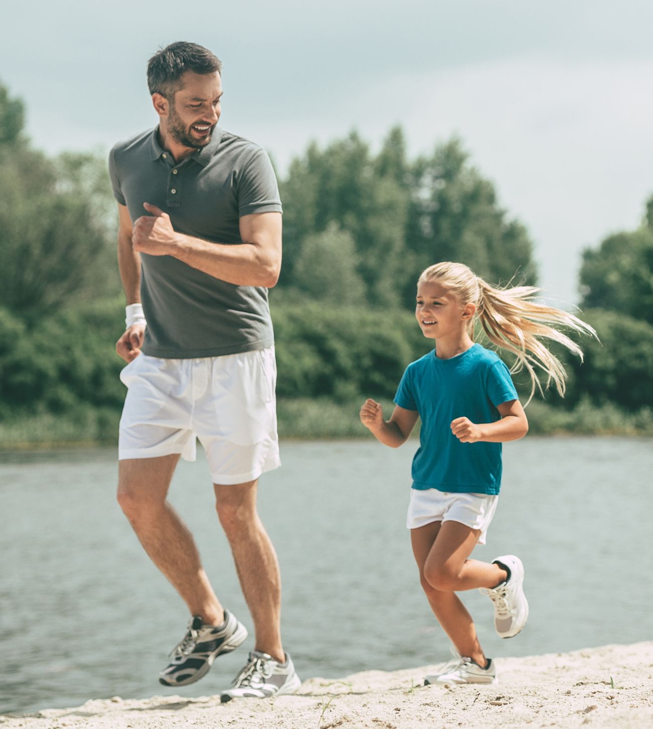 Photo of a dad with his elementary-school-aged daughter on a run together at the beach.