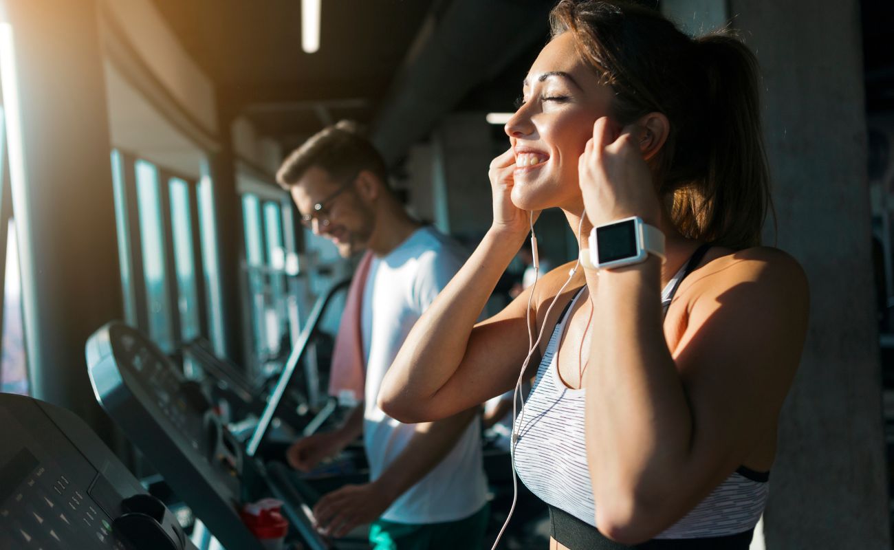 Photo of a woman inside a gym in the cardio area preparing to listen to tunes while she gets a workout in.