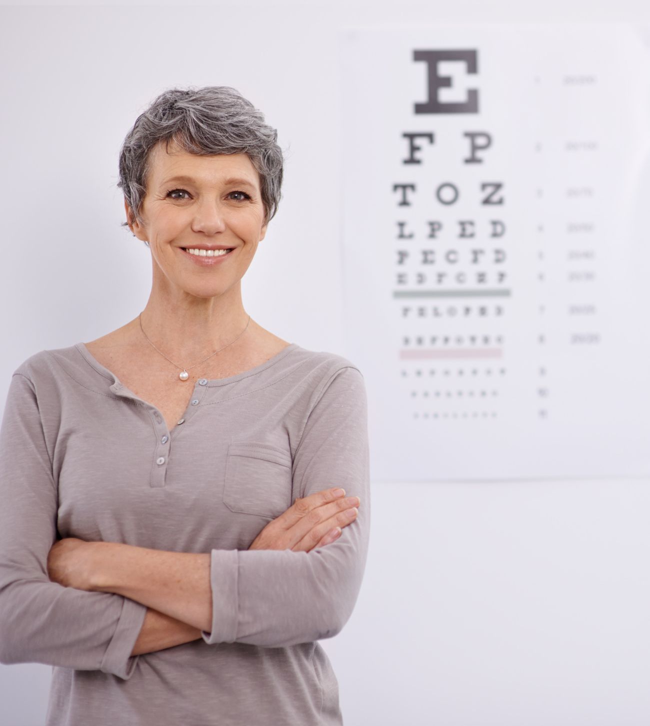 Photo of a middle-aged woman standing beside an eye chart at the ophthalmologist's office