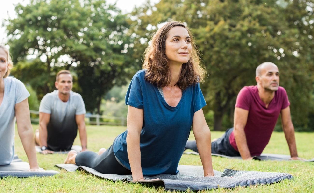 Photo of a group of adult men and women outdoors on the lawn in the midge of a yoga class.
