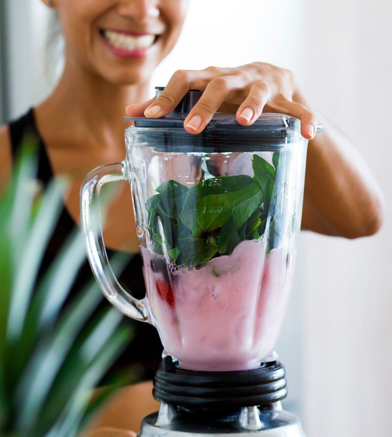Photo of woman blending together a berry and fresh spinach smoothie.