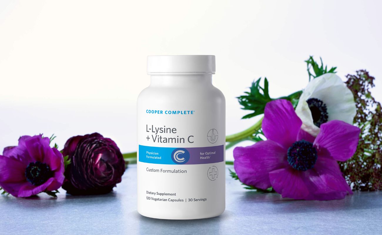 Photo of Cooper Complete L-Lysine Plus Vitamin C Supplement bottle surrounded by beautiful flowers