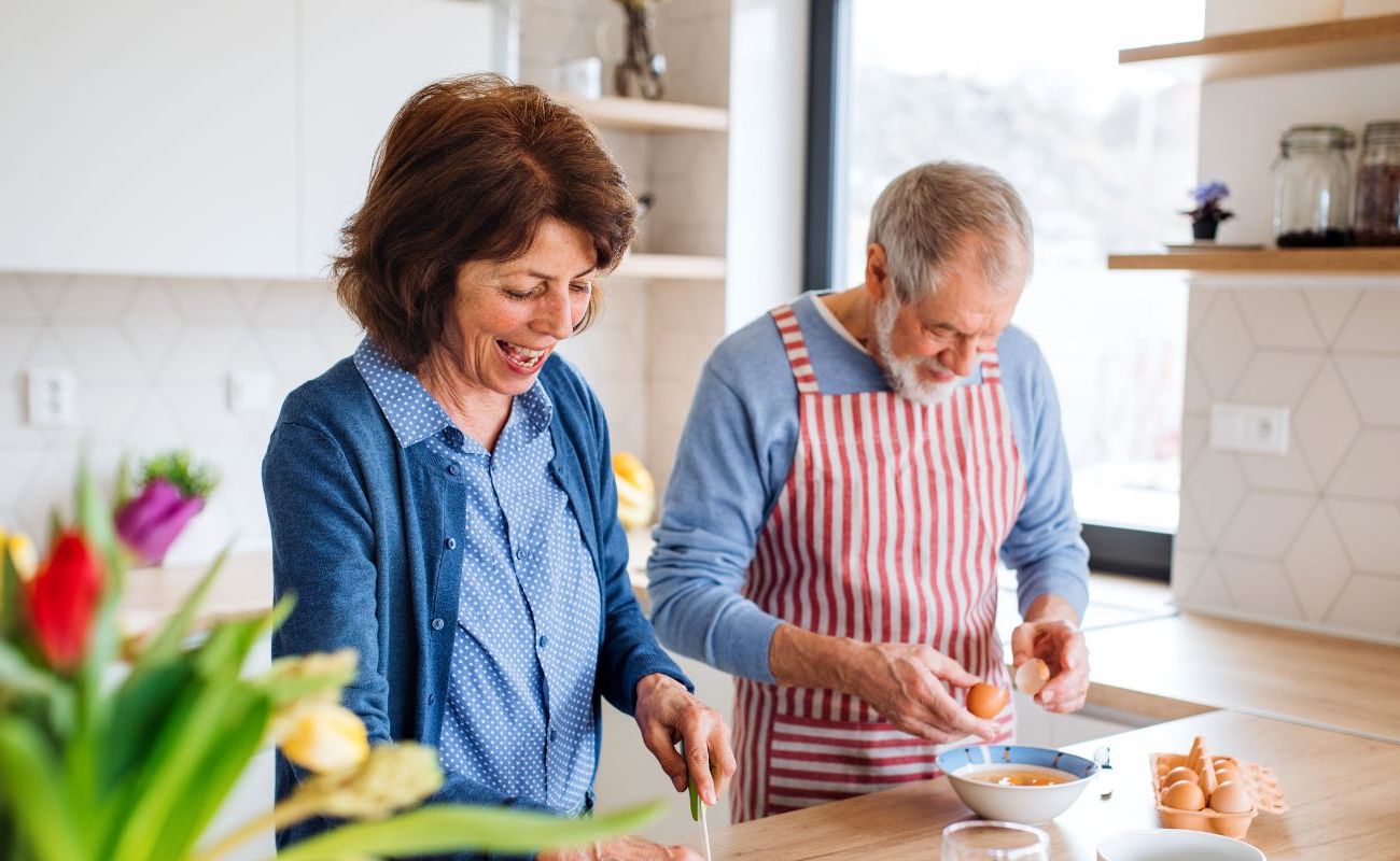 Photo of a mature man and woman prepping a meal together in the kitchen.