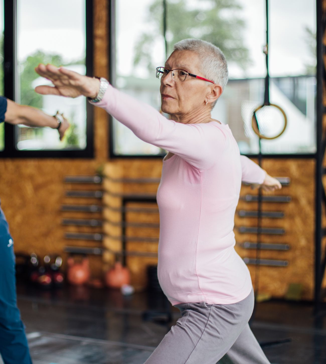 Photo of a mature woman in a yoga or tai chi pose in an exercise studio.