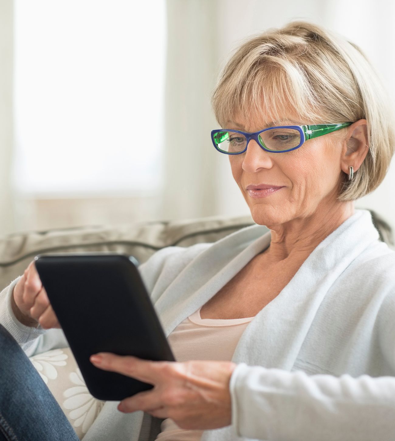 Photo of a mature woman reading on her tablet.