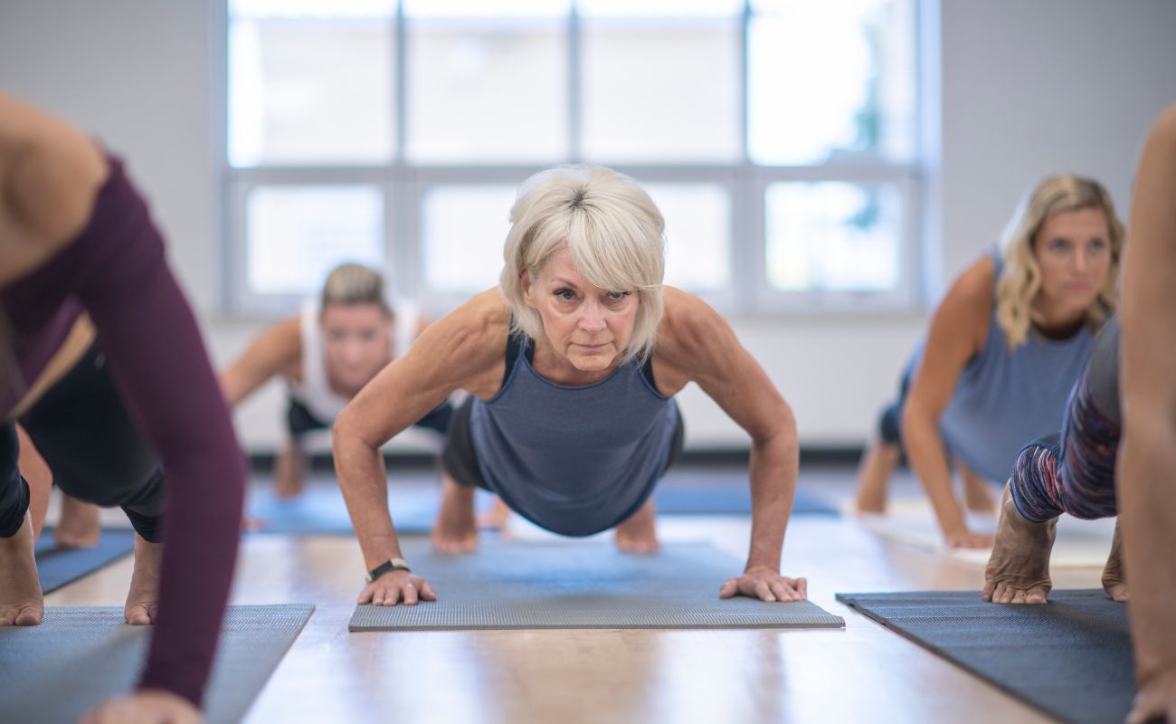 Photo focused on a mature woman in a yoga class where the class is in the middle of holding the plank position.