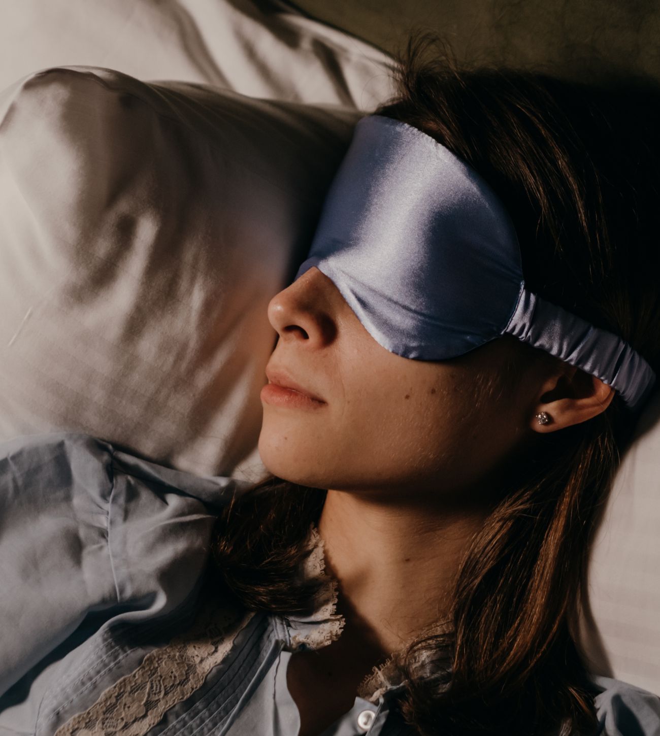 Photo of a younger woman wearing a sleep mask asleep on the bed