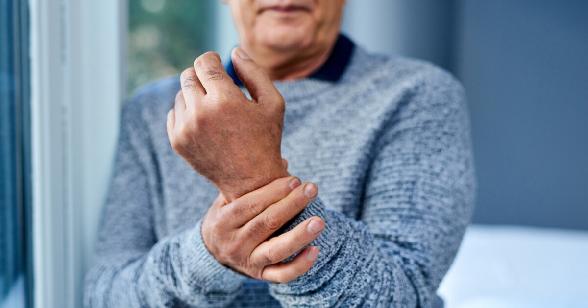 Photo of an older man with his fingers clasping his wrist as if it hurts.