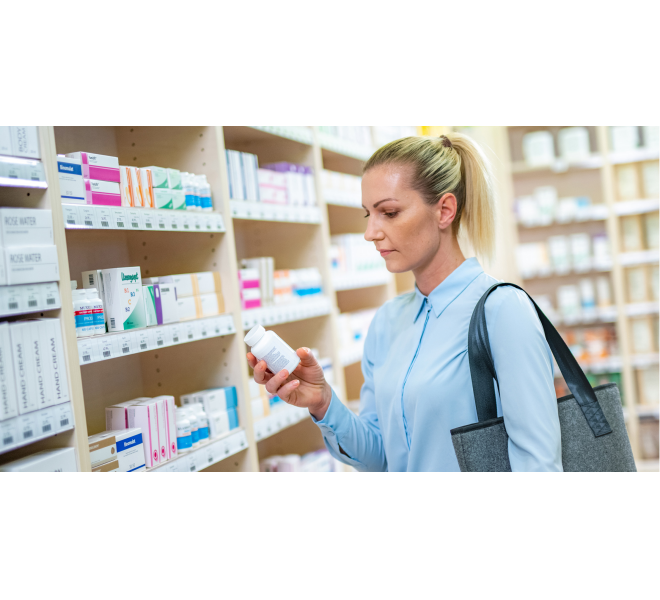 Photo of a woman reading supplement bottle labels in the pharmacy.