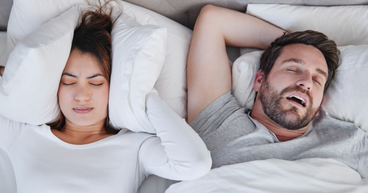 Photo of a couple seemingly uncomfortably sleeping in bed.