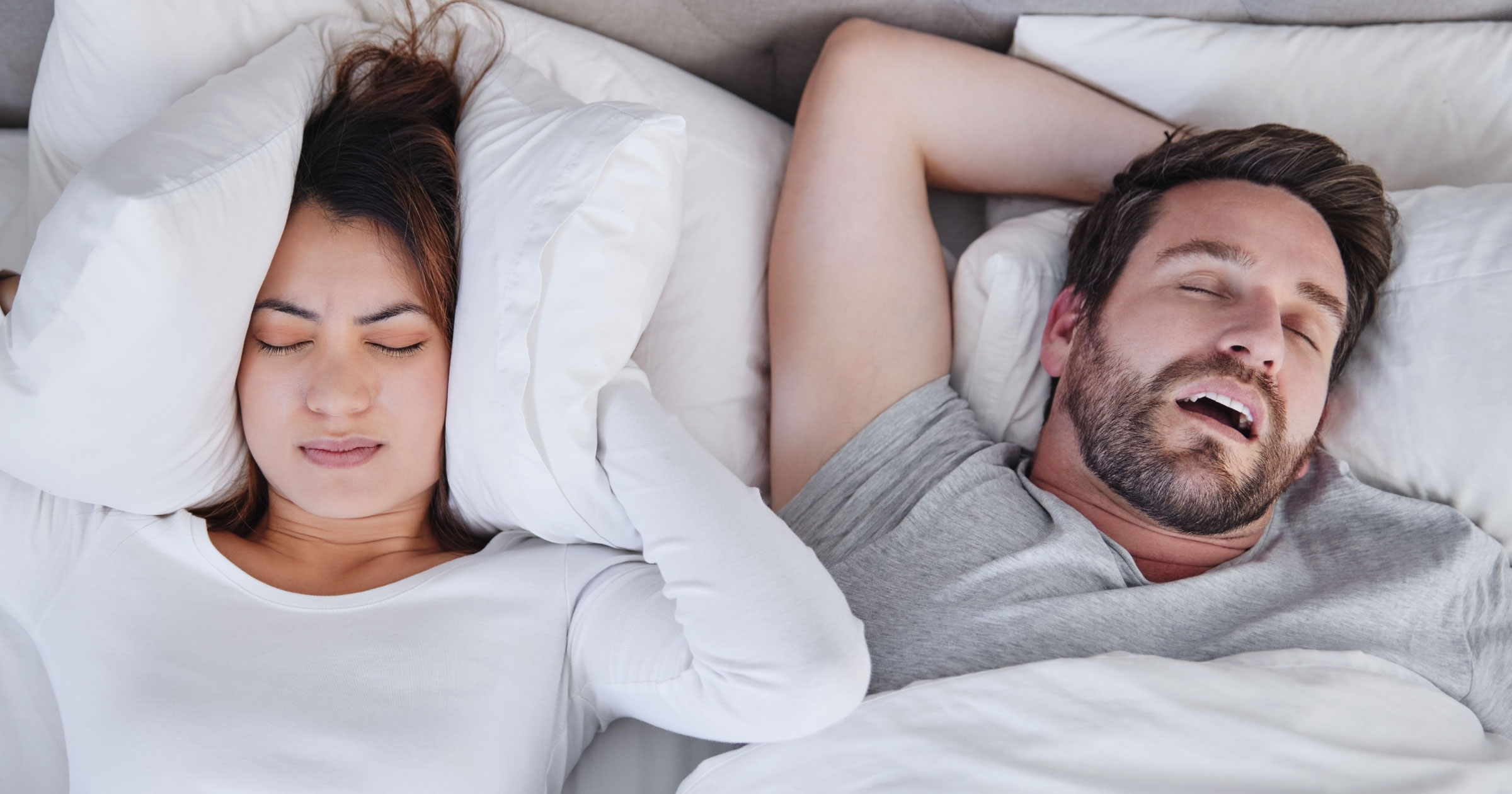 Photo of a couple seemingly uncomfortably sleeping in bed.